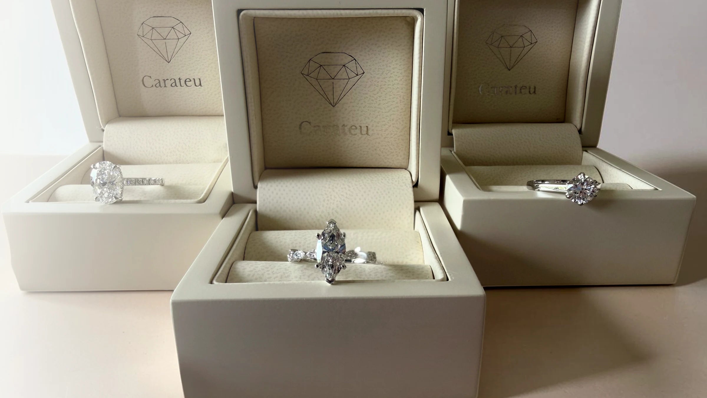 Three Carateu engagement rings displayed in cream ring boxes